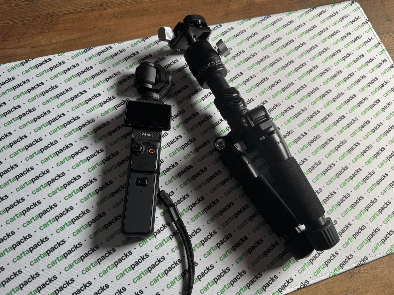 The cartapacks recording rig laid out on the branded playmat: DJI Osmo Pocket and tripod arm, top-down.